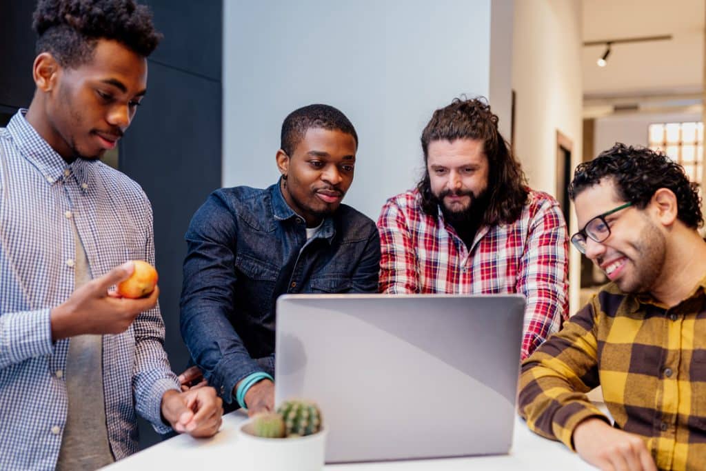 Group of coworkers collaborating at a computer, representing companies contributing to COFINS in Brazil.