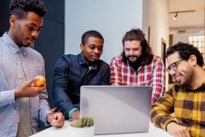 Group of coworkers collaborating at a computer, representing companies contributing to COFINS in Brazil.